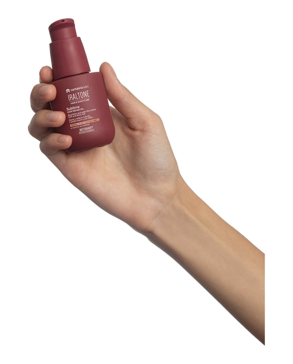 IRALTONE Sublime plaukų aliejus 50 ml laikomas rankoje